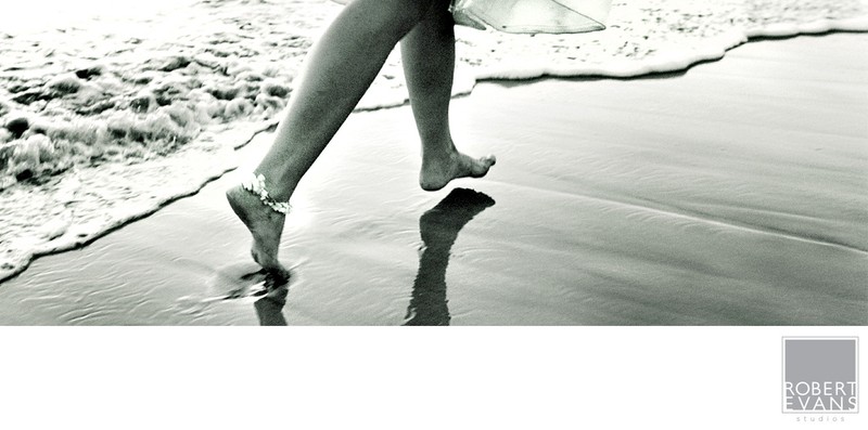 Bare feet walking along the shoreline, reflected in wet sand beside the surf Bare feet walking along the shoreline, reflected in wet sand beside the surf