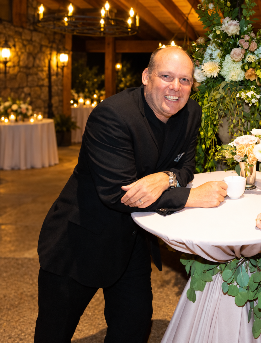 Robert Evans smiling and leaning on a flower-lined reception table at The Broadmoor Robert Evans smiling and leaning on a flower-lined reception table at The Broadmoor