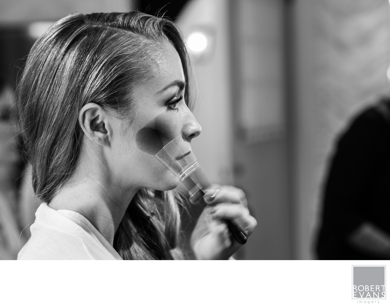 Black-and-white photograph of a bride having her makeup applied.