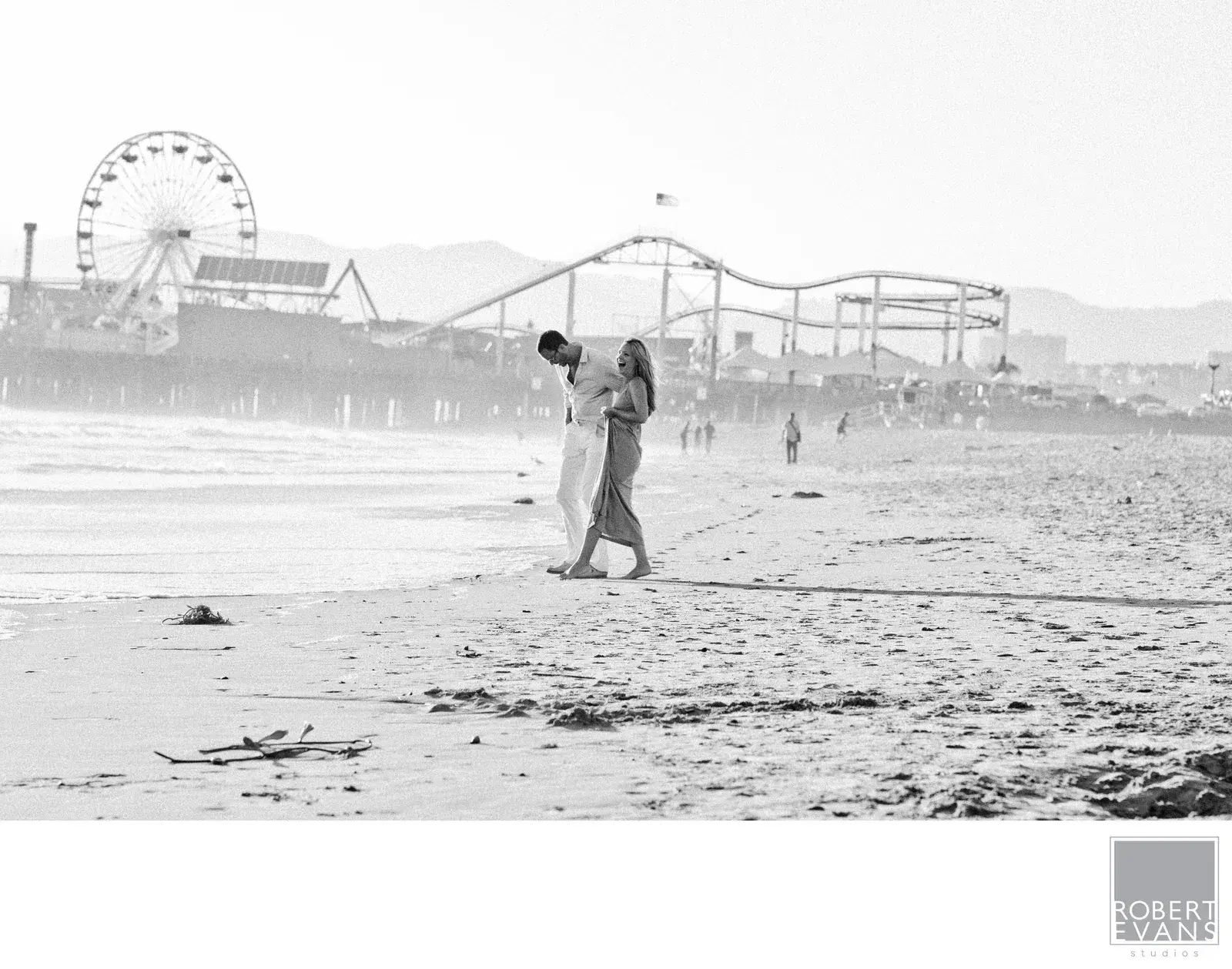 Couple walking on a beach near a pier Couple walking on a beach near a pier