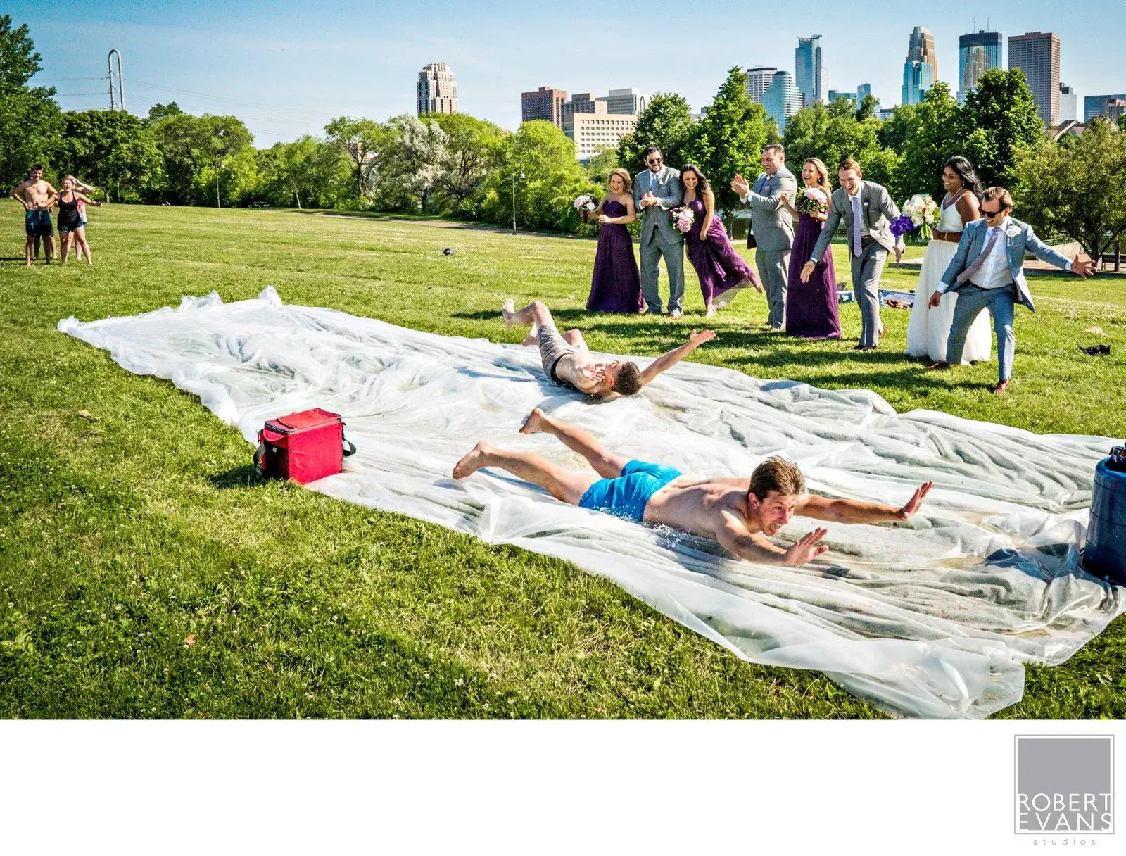 Wedding guests sliding across a lawn beside a city skyline Wedding guests sliding across a lawn beside a city skyline