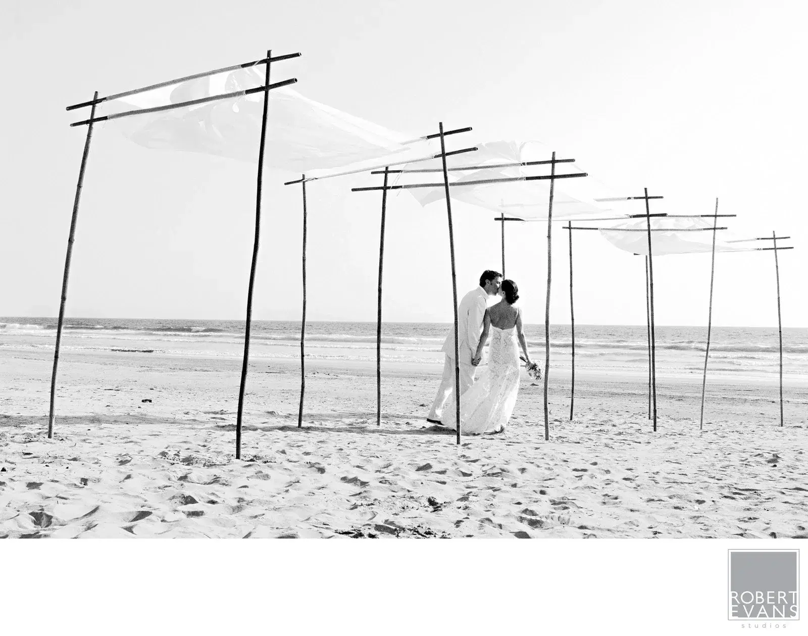 A bride walking among slender wooden structures on the beach A bride walking among slender wooden structures on the beach